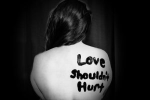 A womans back with the words Love Shouldn't Hurt" used to illustrate blog on Domestic Violence Awareness Week